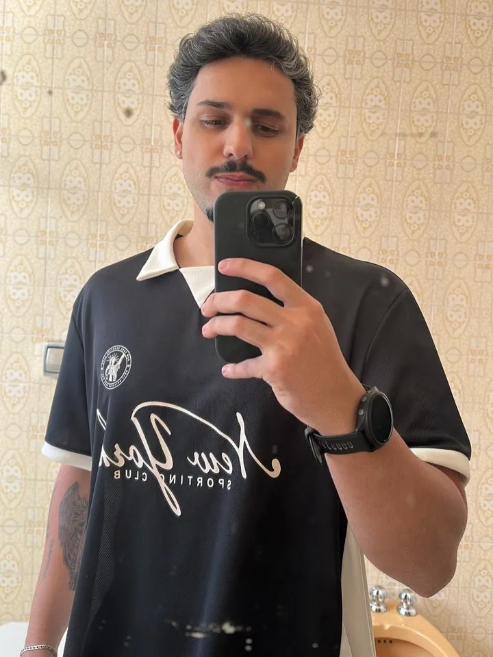 Módulo 3: o Professor de bigode e camisa New York Sporting Club no espelho de um banheiro bege
